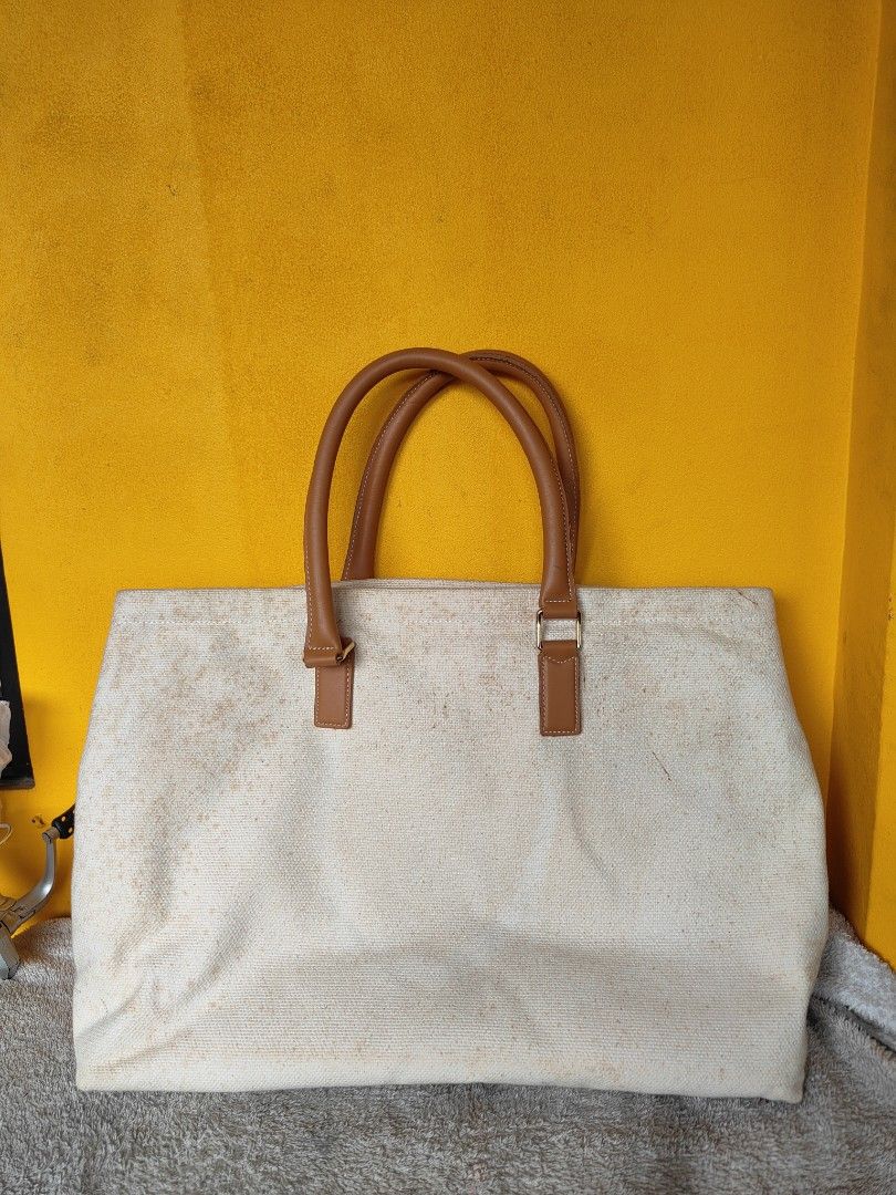 Celine Paris Canvas Tote Bag with Padlock (Category: Tote Bags) located in Cebu City. Submitted by cherreymie70208 (Listing ID 1469856645, Image 2). Description: - Brand: Celine Paris - Material: Cream canvas with brown leather handles - Design: Bold black lettering on the front - Inclusions: Gold padlock with keys on leather clochette, original dust bag, and card - Condition: Substantial staining and discoloration spread across the canvas fabric