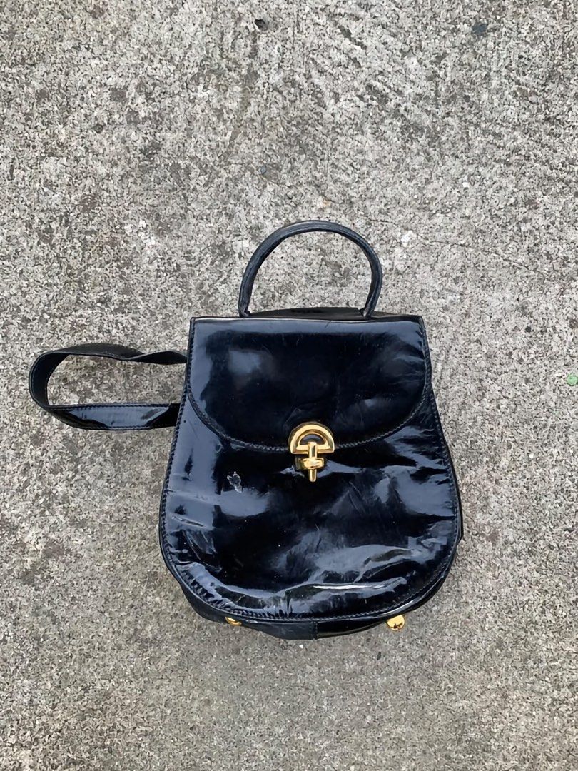Celine Vintage Black Patent Leather Backpack (Category: Backpacks) located in Iba. Submitted by thriftcoyan (Listing ID 1469807191, Image 1). Description: vintage Black patent leather backpack from Celine. Gold hardware closure engraved with the brand name. Top handle plus shoulder straps. Inside lined in bright red leather with a zippered pocket. Celine Paris Made in Italy leather tag inside with serial code F/05 stamped on the back. - Nandiyan 