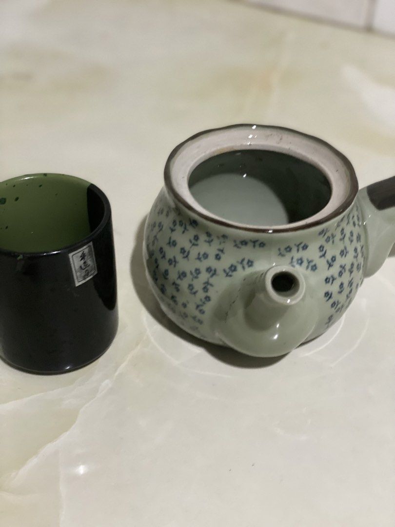 Ceramic Teapot with Matching Cup Set (Category: Coffee & Tea Tableware) located in Manila. Submitted by geminibibo (Listing ID 1469862015, Image 2). Description: - Green ceramic teapot featuring a delicate blue floral pattern and unique side-handle design - Includes a tall matching cup with a sleek black exterior and green interior - Perfect solo tea set for one person - Clean interior, ready for immediate brewing - Pre-loved and well-maintained 