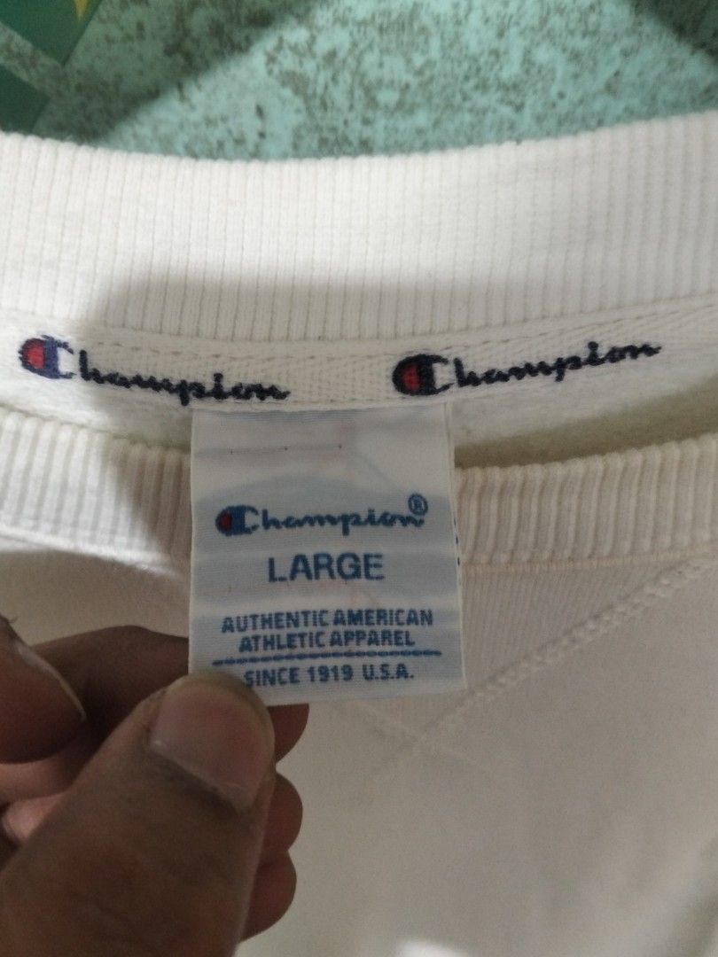 Champion C3-K340 White Sweatshirt Large Big Back Script Logo (Category: Coats, Jackets and Outerwear) located in Baguio. Submitted by jnjayceelbrn (Listing ID 1469837281, Image 3). Description: - Brand: Champion - Style Code: C3-K340 - Size: Large - Material: 100% Cotton - Design: Embroidered mini logo on chest and large blue script logo across the back - Details: Ribbed cuffs and hem - Condition: Pre-owned with noticeable yellowish stains near t