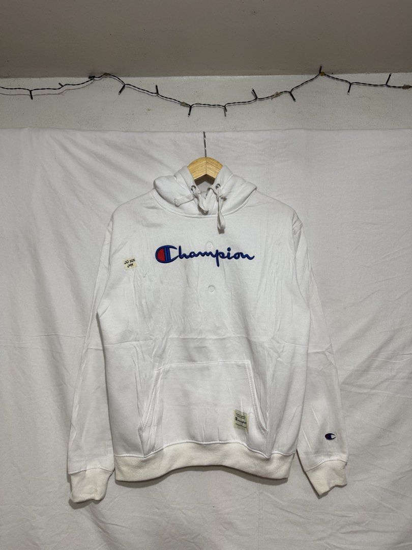 Champion White Script Logo Hoodie (Category: Hoodies) located in Quezon City. Submitted by dapanaaaay (Listing ID 1469927962, Image 1). Description: - Color: Clean white with blue embroidered Champion script logo across the chest - Features: Front kangaroo pocket, drawstring hood with metal eyelets, and ribbed cuffs and hem - Branding: Iconic small embroidered Champion patch on the left sleeve cuff and woven label near the hem - Style: Classic st
