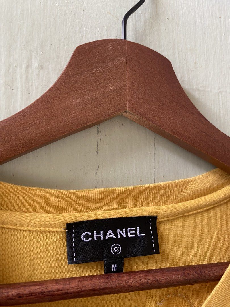 CHANEL Pharrell Yellow Graphic T-shirt Size M (Category: Tshirts & Polo Shirts ) located in Pandi. Submitted by nasya_thrift_collection2023 (Listing ID 1469770736, Image 3). Description: - Brand: Chanel Pharrell Collection - Item: Yellow Crewneck T-Shirt - Size: Medium (Relaxed fit) - Material: 100% Cotton, Made in Italy - Design: Colorful sequin 'Pharrell' and 'Chanel' lettering on the front - Detail: Signature 'Coco' embroidery near the back co