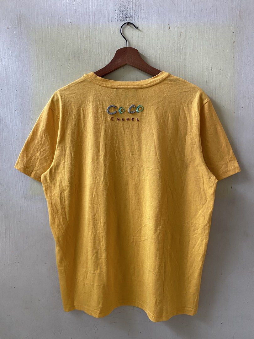 CHANEL Pharrell Yellow Graphic T-shirt Size M (Category: Tshirts & Polo Shirts ) located in Pandi. Submitted by nasya_thrift_collection2023 (Listing ID 1469770736, Image 2). Description: - Brand: Chanel Pharrell Collection - Item: Yellow Crewneck T-Shirt - Size: Medium (Relaxed fit) - Material: 100% Cotton, Made in Italy - Design: Colorful sequin 'Pharrell' and 'Chanel' lettering on the front - Detail: Signature 'Coco' embroidery near the back co
