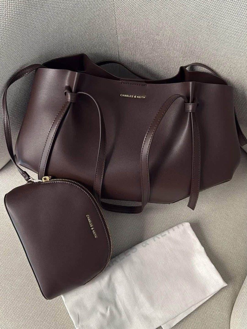 Charles & Keith Dark Brown Tote Bag with Pouch (Category: Tote Bags) located in Pagsanjan. Submitted by jecay00 (Listing ID 1469887277, Image 2). Description: - Brand: Charles & Keith - Color: Rich dark brown - Material: Premium leather - Design: Clean minimalist style with a structured body and thin shoulder straps - Includes: Matching crescent-shaped zip pouch and original dust bag - Features: Spacious interior, perfect for daily essentials - C
