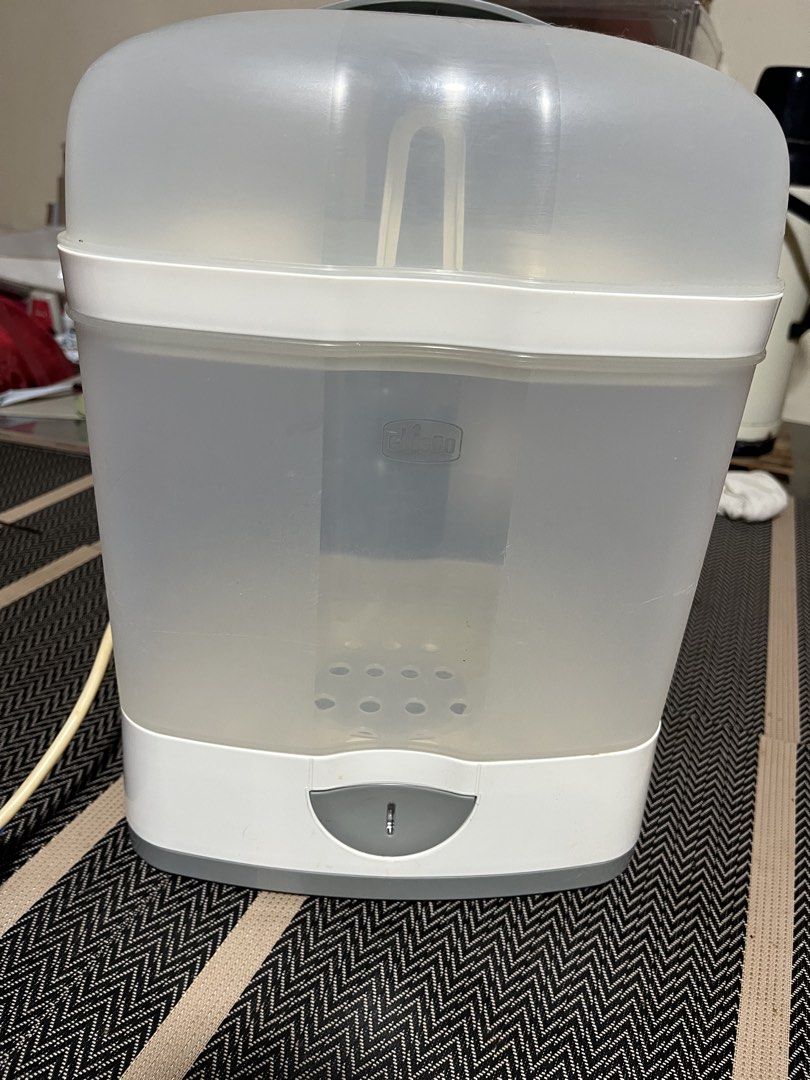 Chicco Electric Bottle Sterilizer (Category: Breastfeeding & Bottle Feeding) located in Imus. Submitted by kyshashop (Listing ID 1469904080, Image 1). Description: Chicco steam sterilizer for baby bottles. Includes base unit, transparent main container, lid, and slotted rack. Has water scale buildup on the heating plate inside the base, typical from regular use. Fully functional steam unit for daily baby feeding prep..