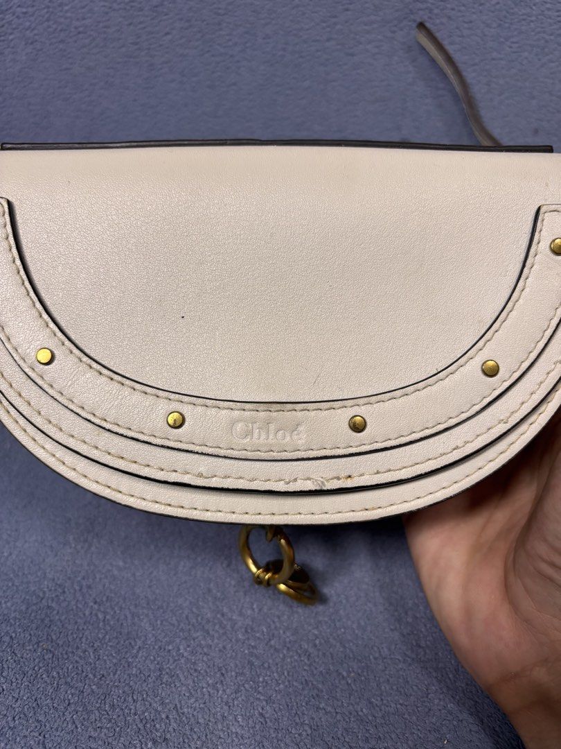 Chloé White Leather Crossbody Bag (Category: Cross-body Bags) located in Mabalacat. Submitted by _limitlessfashion (Listing ID 1469778155, Image 2). Description: White leather saddle bag from Chloé. Semi-circle shape with gold-tone hardware, studs, and hanging charms. Includes a chain and leather strap. Back pocket detail. Made in Italy stamp on the charm..