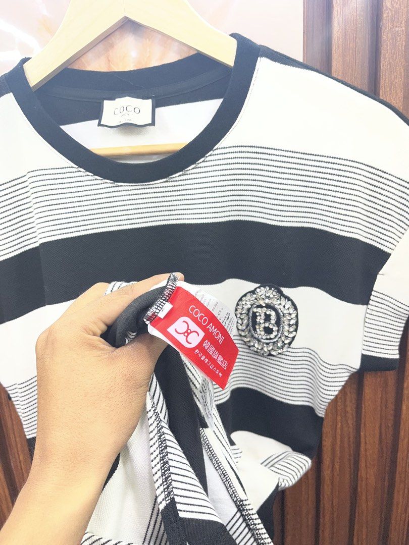 Coco Amoni black and white striped dress (Category: Dresses) located in Kidapawan. Submitted by azythrift (Listing ID 1469864963, Image 3). Description: - Brand: Coco Amoni - Design: Black and white stripes with short sleeves and round neckline - Details: Eye-catching crystal crest badge on the chest and flattering ruched side detail - Length: Midi length - Material: Comfortable cotton blend knit - Condition: Brand new with neck tag and care tags