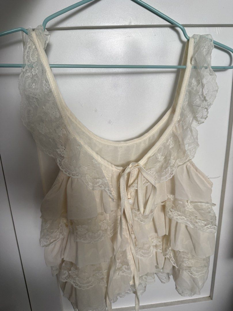 Cream Lace Ruffle Layered Sleeveless Top (Category: Sleeveless) located in Pasig City. Submitted by atbp__ (Listing ID 1469810009, Image 1). Description: - Cream layered camisole with sweet ruffle and lace details best fits small - Scoop neckline featuring front ribbon ties and small functional buttons - Super soft, lightweight, and breathable fabric - Perfect for layering or as a standalone top on warm days - Clean condition with no obvious flaw
