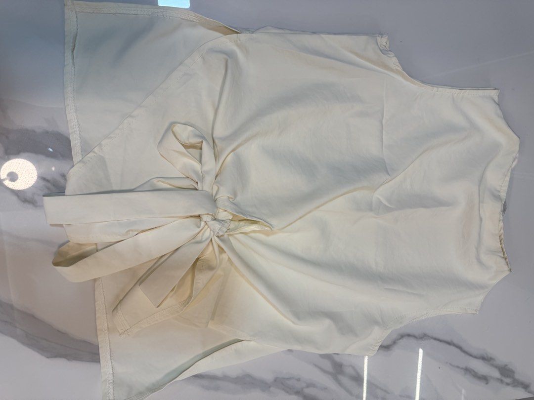 Cream Sleeveless Wrap Blouse with Side Tie (Category: Blouses) located in Manila. Submitted by decluterthings888 (Listing ID 1469761209, Image 1). Description: - Color: Cream ❌ NO BRAND ❌ - Style: Sleeveless wrap front with built-in side tie sash - Fabric: Lightweight and comfortable - Fit: Pairs perfectly with high-waisted pants or skirts - Condition: Clean, like-new, no stains or loose threads.