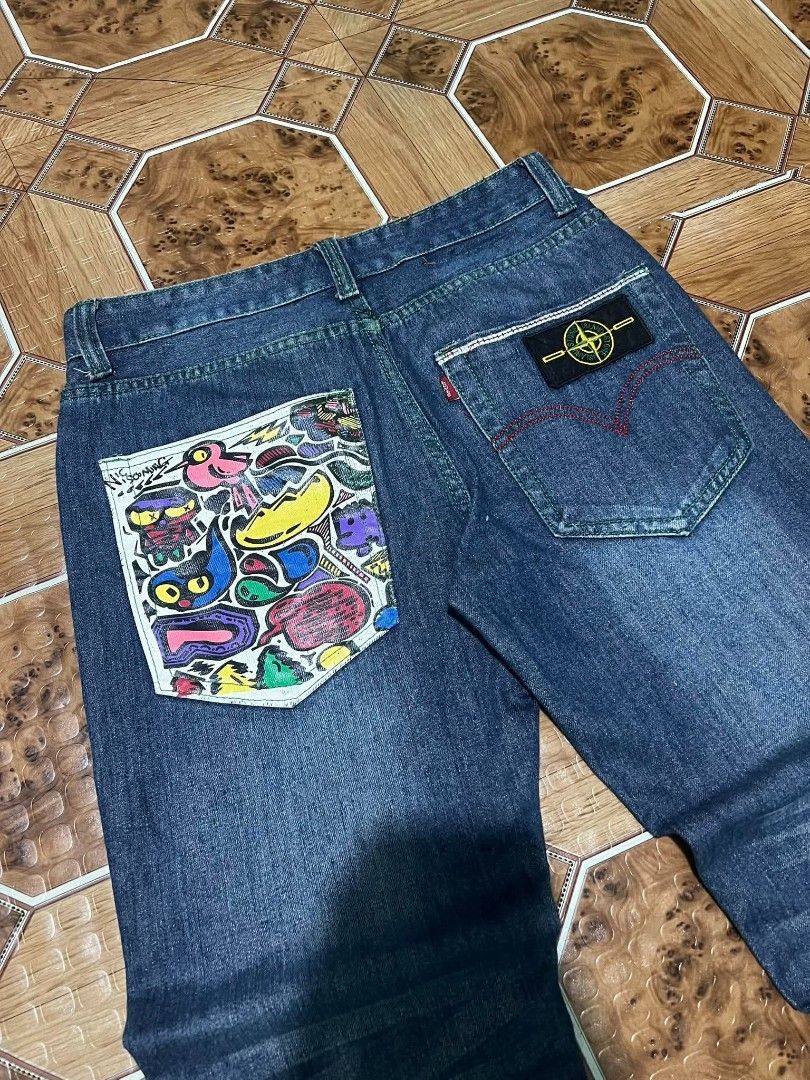 Custom Printed Denim Jeans with Red Cuffs (Category: Jeans) located in Cagayan de Oro. Submitted by friderickv99131 (Listing ID 1469920608, Image 3). Description: Dark wash denim jeans, straight fit. Custom graffiti art printed on one back pocket and front leg. Red satin cuffs with skull prints rolled at the bottom. Green contrast stitching and neon green button accents. Back pocket includes a Stone Island style compass patch..