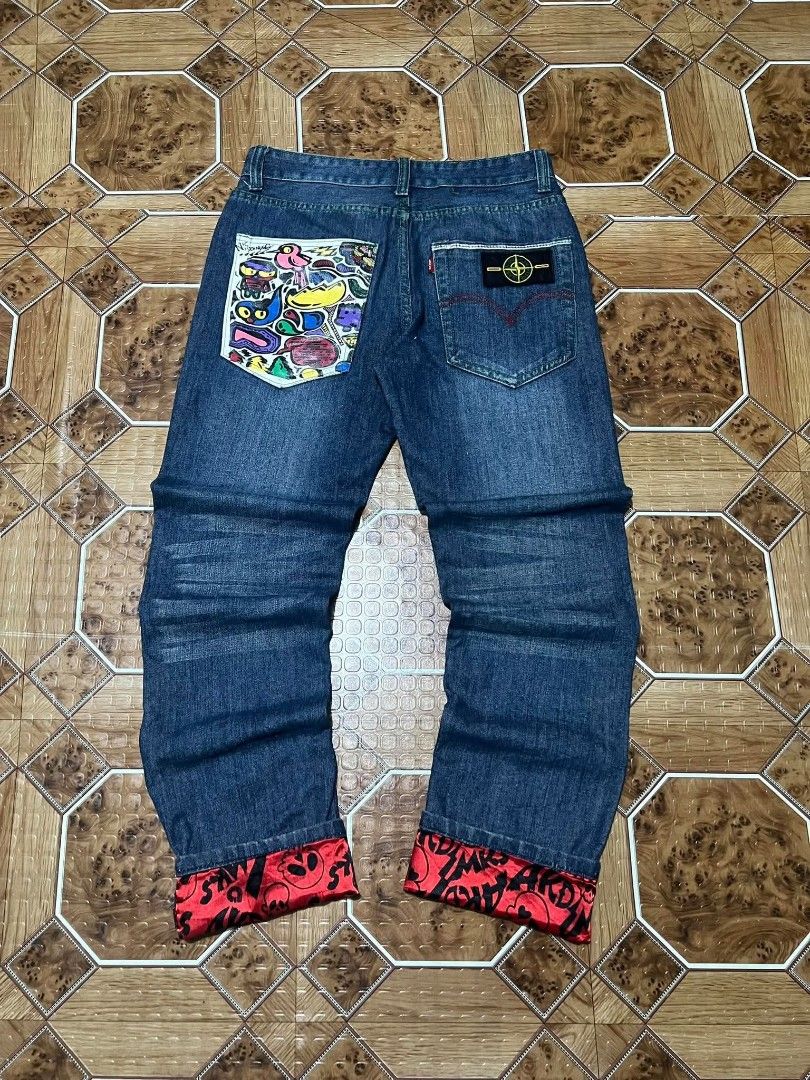 Custom Printed Denim Jeans with Red Cuffs (Category: Jeans) located in Cagayan de Oro. Submitted by friderickv99131 (Listing ID 1469920608, Image 2). Description: Dark wash denim jeans, straight fit. Custom graffiti art printed on one back pocket and front leg. Red satin cuffs with skull prints rolled at the bottom. Green contrast stitching and neon green button accents. Back pocket includes a Stone Island style compass patch..