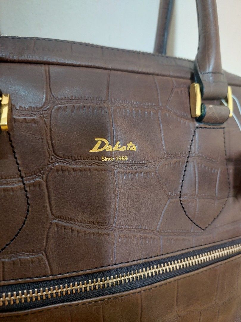 Dakota Since 1969 Brown Crocodile Pattern Leather Handbag (Category: Luxury Bags & Wallets) located in Malabon City. Submitted by jullie_bag_shop (Listing ID 1469817645, Image 2). Description: - Brand: Dakota - Color: Dark Brown - Material: Embossed faux crocodile leather - Hardware: Gold-tone - Features: Double handle drop, secure zip-around closure, and front vertical zip pocket - Interior: Fabric-lined with multiple slip and zip pockets - Cond