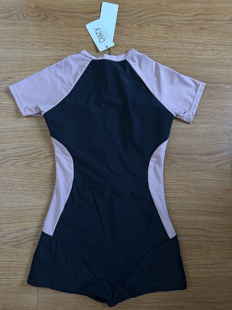 Dazy Short Sleeve Zip Front Swimsuit Romper (Category: Bikinis & Swimsuits) located in Mandaluyong City. Submitted by unworntobarelyworn (Listing ID 1469858415, Image 3). Description: - Brand: Dazy - Condition: Brand new with tags, never worn - Size: S - Design: Black and pink contrast with solid color-blocking along the sides - Features: Front zipper closure, short sleeves, and built-in shorts style.