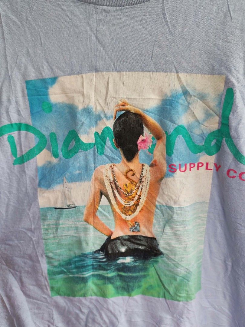 Diamond Supply Co. Graphic T-Shirt Light Blue (Category: Tshirts & Polo Shirts ) located in Sipalay. Submitted by boldowl.e4f283 (Listing ID 1469809190, Image 2). Description: - Brand: Diamond Supply Co. - Color: Light Blue - Size: Large - Design: Large graphic print of person with tiger tattoo, accented with teal and red logo lettering - Fit: Relaxed fit with classic crewneck - Details: Signature Diamond logo tag near bottom hem - Material: Soft