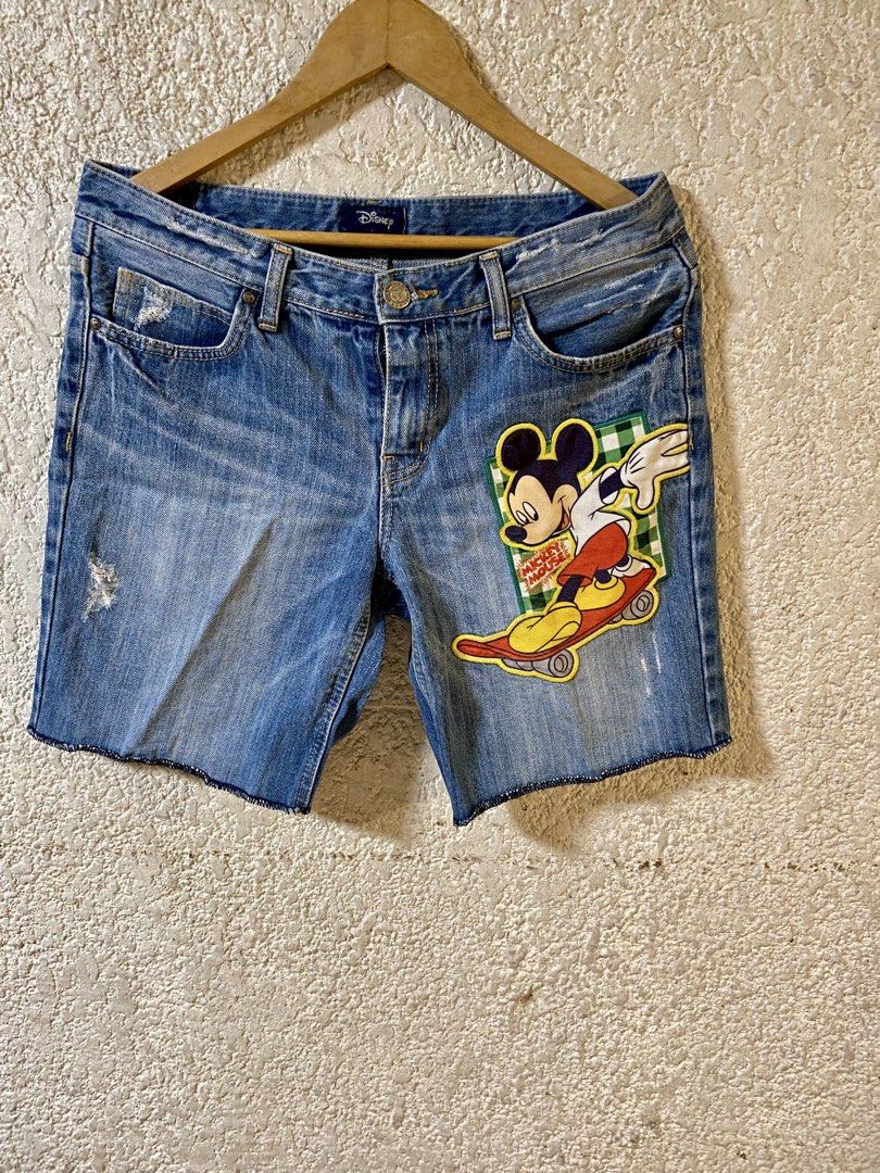 Disney Mickey Mouse Denim Shorts (Category: Shorts) located in Navotas City. Submitted by bayxsell (Listing ID 1469809535, Image 2). Description: - Official Disney denim shorts - Skater Mickey Mouse patch on the front leg - Embroidered Mickey Mouse text above the back pocket - Trendy distressed details with a raw hem - Mid-rise waist with standard button and zip closure - Condition: Brand new / Excellent (Ready to ship!).