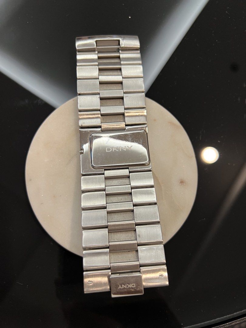 DKNY Silver Wide Cuff Watch (Category: Women's Watches) located in Manila. Submitted by pearlt455 (Listing ID 1469771119, Image 2). Description: - Authentic silver DKNY statement watch - Bold and wide brick-link cuff bracelet style - Textured dial with minimalist hands and markers - Secure clasp closure signed with the iconic DKNY logo - Condition: Normal surface wear from use, still looks striking on the wrist.