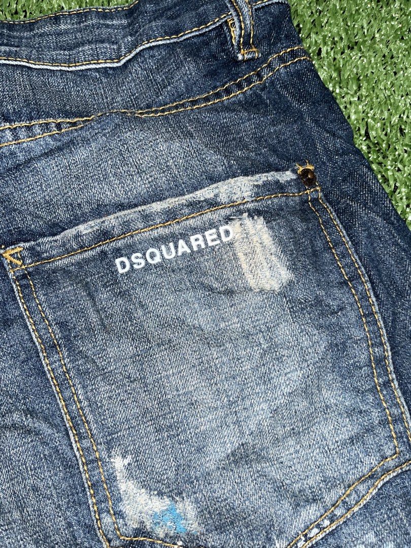 DSQUARED2 Distressed Denim Shorts Paint Splatter (Category: Shorts) located in Manila. Submitted by nevahhbrokeagain (Listing ID 1469890899, Image 3). Description: - Brand: DSQUARED2 - Item: Distressed Denim Shorts - Wash: Dark blue with unique white and blue paint splatter details - Features: Distressed patches, contrasting yellow stitching, button fly with branded tab, rear pocket embroidery, and DSQUARED logo text on back pocket - Material: He