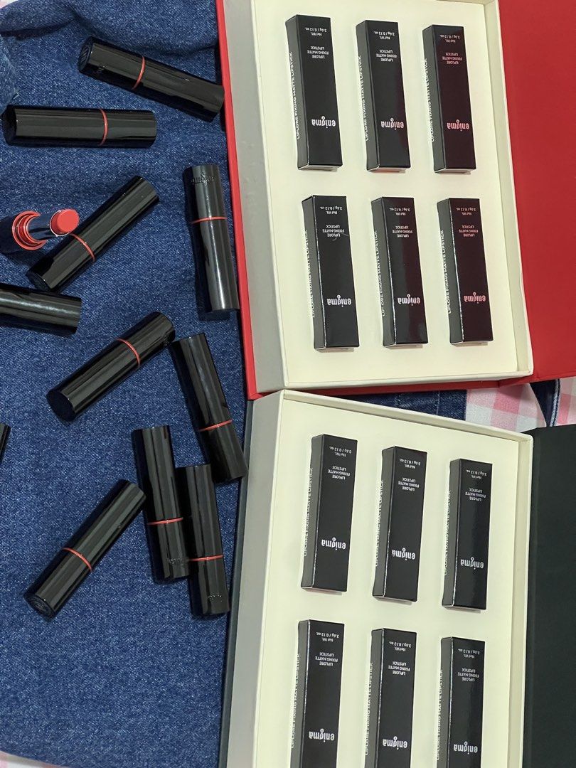 Enigma Liplore Fixing Matte Lipstick Set (Category: Makeup) located in Manila. Submitted by andeng30 (Listing ID 1469872119, Image 1). Description: - Brand: Enigma Liplore - Type: Fixing Matte Lipstick Collection - Bundle includes: 2 full presentation boxes with boxed lipsticks and multiple loose tubes - Shade shown: Vibrant coral-red (one tube uncapped) - Packaging: Heavy black tubes featuring a chic red ring detail on the caps - Condition: Bran