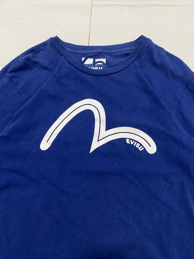 Evisu Blue T-Shirt (Category: Tshirts & Polo Shirts ) located in Manila. Submitted by morsgotthrift (Listing ID 1469796030, Image 2). Description: - Authentic Evisu short sleeve tee in royal blue - Large white seagull logo on the chest with a small logo hit on the upper back - Tagged size 90 - Made from soft cotton fabric with a comfortable ribbed crew neckline - Clean and stylish piece for casual streetwear looks.