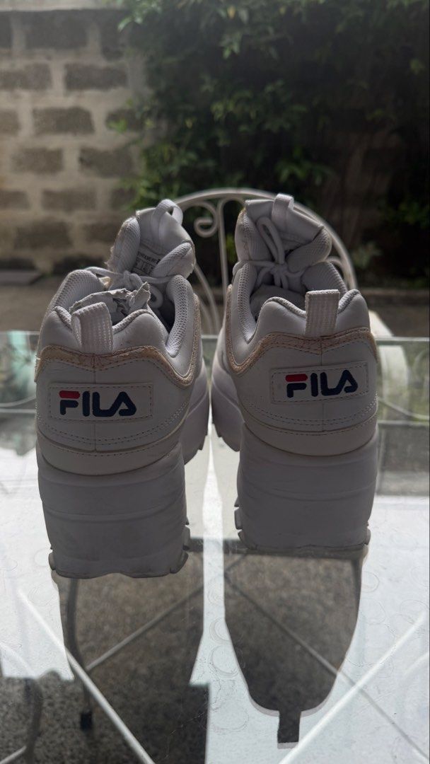 Fila Disruptor 2 Wedge White Sneakers US 9 (Category: Sneakers) located in Calamba. Submitted by rafabariso (Listing ID 1469759677, Image 2). Description: - Brand: Fila Disruptor 2 Wedge - Color: White - Size: US 9 (27.0 cm) - Style: Chunky platform with iconic branding on tongue, side, and heel pull - Inclusions: Original shoe box - Condition: Moderate wear with visible scuffs and creasing on uppers, plus dirt on rubber outsoles.