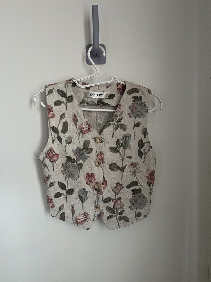 Floral Button Vest (Category: Sleeveless) located in Lapu Lapu. Submitted by alexisdeclutters (Listing ID 1469787924, Image 1). Description: - Brand: YEA DAY - Color/Design: Neutral beige with all-over pink and blue rose print with green leaves - Style: Sleeveless V-neck vest with a trendy cropped hem - Closure: 4 round wooden-style front buttons - Condition: Excellent/Brand new with tag -.