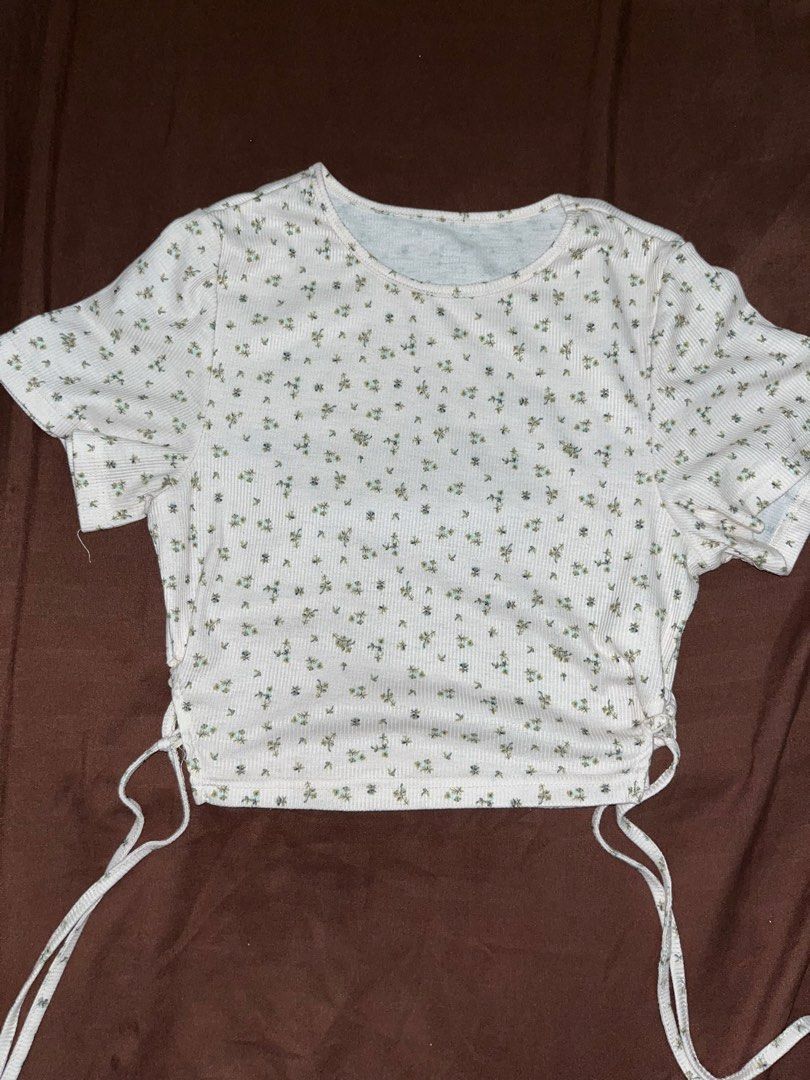 Floral Print Ribbed Crop Top with Side Drawstrings (Category: Others Tops) located in Manila. Submitted by shenaclothes. (Listing ID 1469885606, Image 1). Description: - Color: White with all-over small floral print - Material: Soft and comfortable ribbed fabric - Fit: Crop top with short sleeves - Feature: Adjustable side drawstrings to customize length - Style: Casual, perfect for hot weather and pairs easily with high-waisted jeans or skirts.