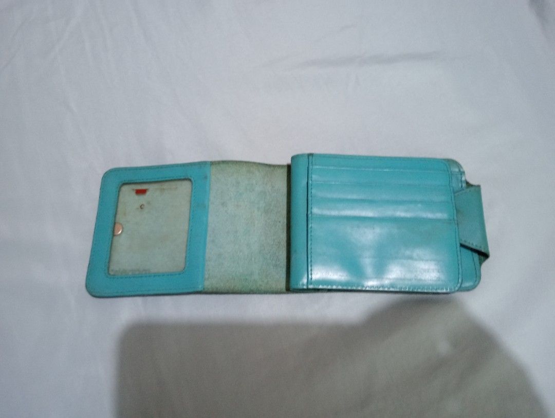 Folding turquoise genuine leather folding wallet card holder (Category: Wallets & Card holders) located in Makati City. Submitted by YSL80022 (Listing ID 1469878760, Image 3). Description: - Brand: Manels - Color: Turquoise - Closure: Side snap button - Features: Multiple card slots, ID window, and bill compartment with dark fabric lining - Condition: Shows visible wear, scuffs, and discoloration on exterior and interior leather, but closure and 