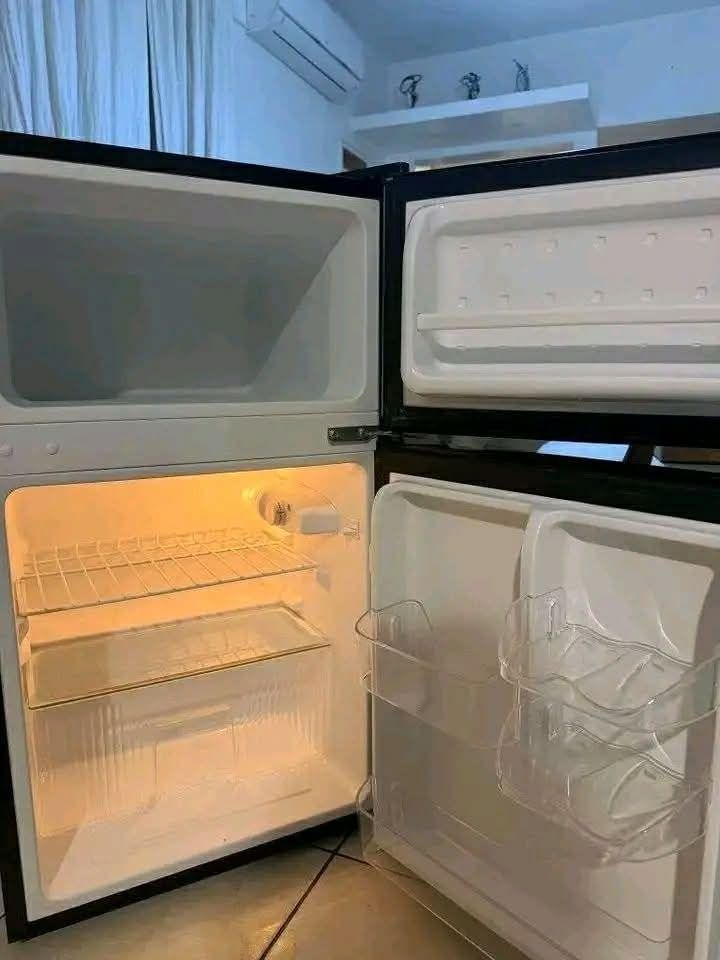 Fujidenzo Mini Two-Door Refrigerator (Category: Refrigerators and Freezers) located in Makati City. Submitted by princess1997_ (Listing ID 1469766650, Image 3). Description: Fujidenzo mini two-door refrigerator in gray with black trim. Compact size fits small kitchen spaces, dorm rooms, or offices. Separate freezer on top and fridge compartment below. Wire shelving and clear door bins included. Temperature control knob located inside. Clean white