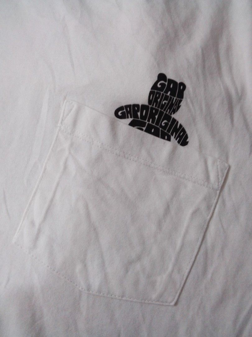 Gap Original Graphic White T-Shirt (Category: Shirts) located in Manila. Submitted by jctclthng_2026 (Listing ID 1469813737, Image 2). Description: - Brand: Gap - Color: White with black all-over typographic graphic - Design: Repeated 'Gap Original' stylized retro font into a best shaped logo - Fit & Style: Standard fit, short sleeves, crew neck - Material: Soft, lightweight, and breathable cotton - Condition: Minimal wear, need wash, no stains o
