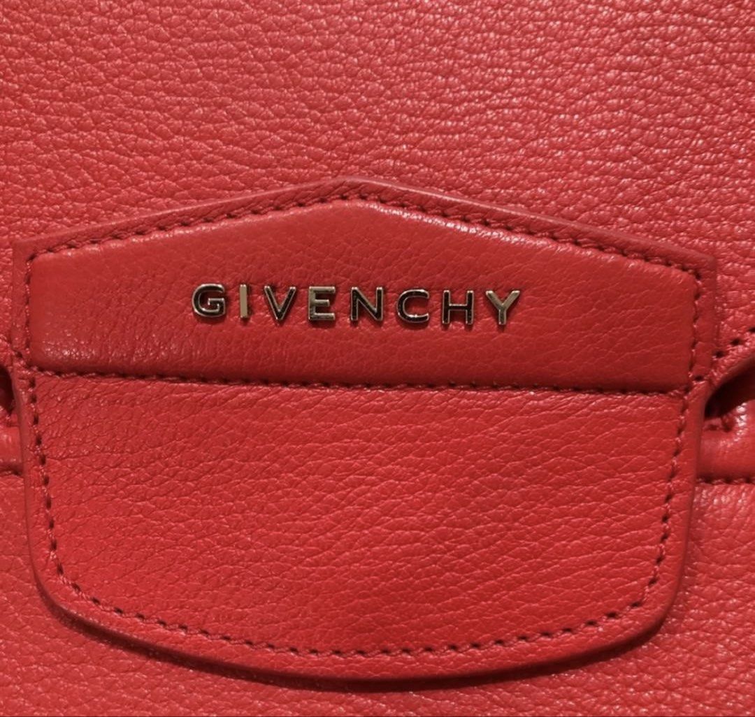 Givenchy Antigona Envelope Clutch in Red (Category: Luxury Bags & Wallets) located in Quezon City. Submitted by kateykate12345 (Listing ID 1469923129, Image 2). Description: - Brand: Givenchy - Material: red pebbled leather - Closure: Envelope flap with front metal branding - Interior: Black lining with 'Made in Italy' stamped leather tag - Condition: Clean exterior and corners - Inclusion: Comes with dust bag, authentication from Poizon - Negoti