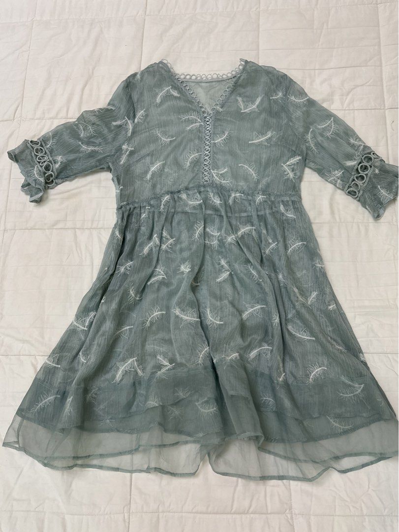 Green Feather Sheer Embroidered Dress (Category: Dresses) located in Quezon City. Submitted by m3gan8 (Listing ID 1469788120, Image 1). Description: - Color: Sage green with white embroidered feather pattern - Material: Lightweight, comfortable fabric - Design: V-neckline with lace trim, half sleeves with circular cutouts - Silhouette: Empire waist, relaxed fit, and flowy tiered hemline - Length: Midi length - Condition: Brand new / Excellent.