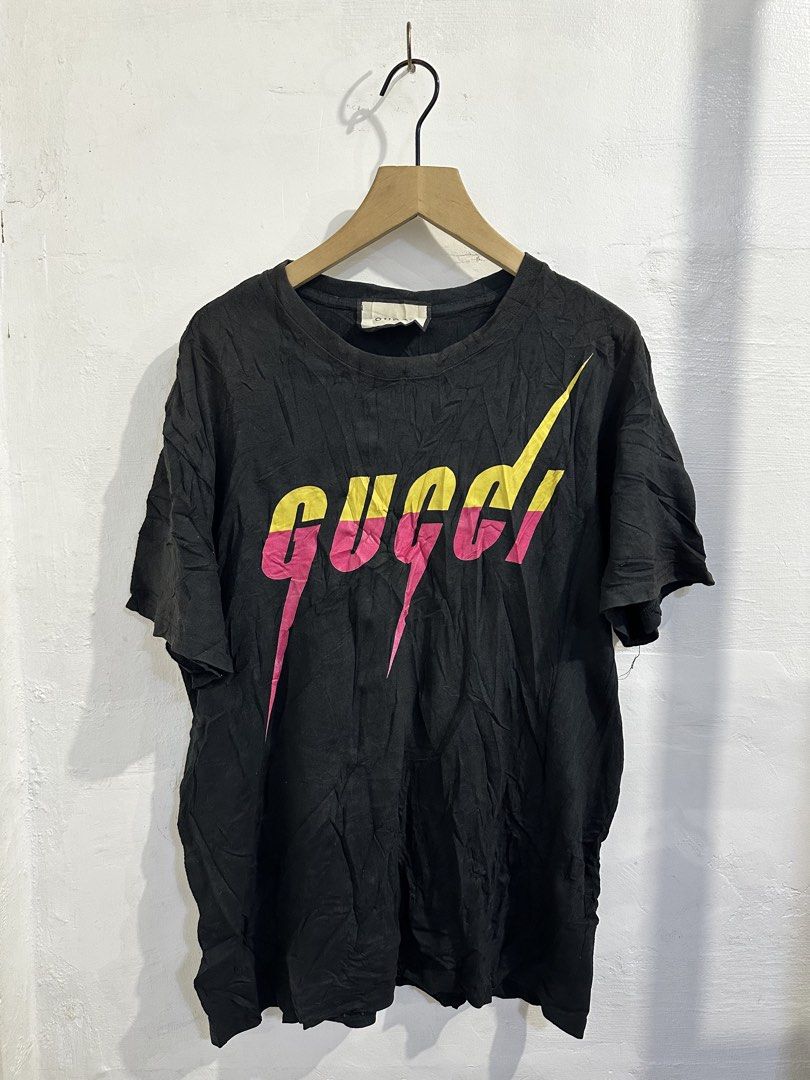 Gucci Black Graphic T-Shirt (Category: Tshirts & Polo Shirts ) located in San Jose del Monte. Submitted by bizzybeebyhgc (Listing ID 1469849021, Image 1). Description: - Color: Black - Material: Cotton - Size: Large 21 x 27 - Design: Colorful stylized dripping logo in yellow and pink on the front - Cut: Short sleeves and crew neck - Condition: Brand new with tags, shows minor wrinkling from storage.