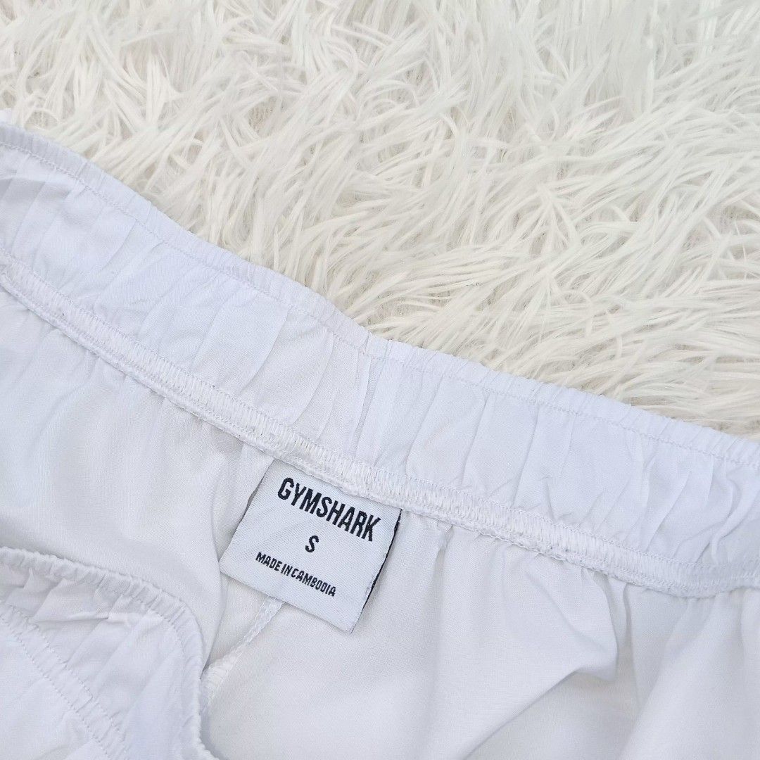 Gymshark White Shorts Size S (Category: Shorts) located in Gattaran. Submitted by thrift_wiseph (Listing ID 1469857090, Image 2). Description: - Brand: Gymshark - Color: Clean White - Size: Small - Material: 100% lightweight polyester - Features: Elastic waistband for a snug fit, printed sharkhead logo on lower left leg - Care: Easy to wash and maintain.