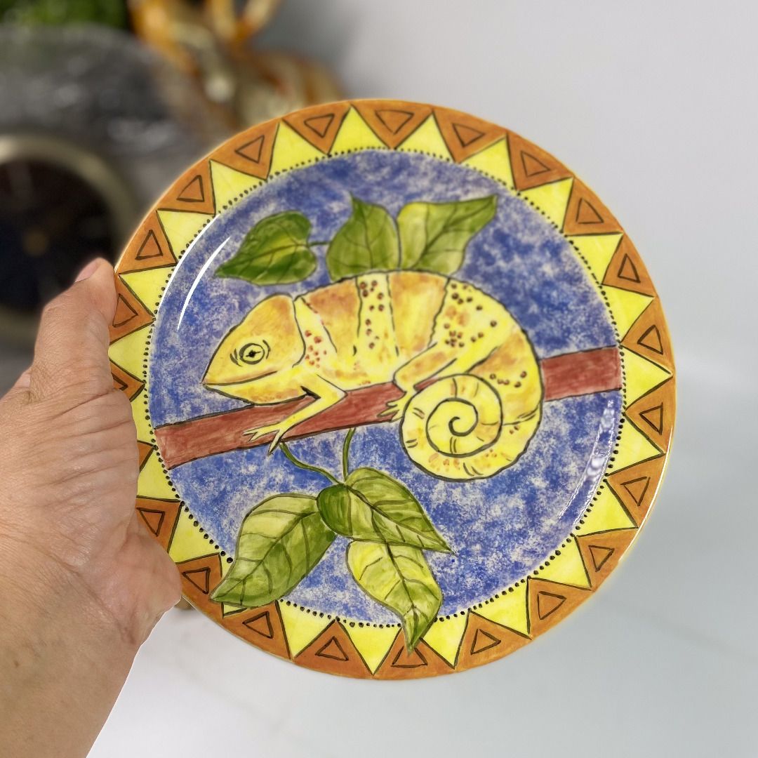 Handpainted Chameleon Ceramic Plate Durban 1997 101426-059 (Category: Dinnerware & Cutlery) located in Quezon City. Submitted by madiscollectibles (Listing ID 1469795187, Image 2). Description: With crazing at the back - Handpainted South African ceramic decorative plate - Features a striking yellow chameleon on a branch with green leaves - Textured blue background with geometric orange and yellow border patterns - Back signed by artist SH (Durba