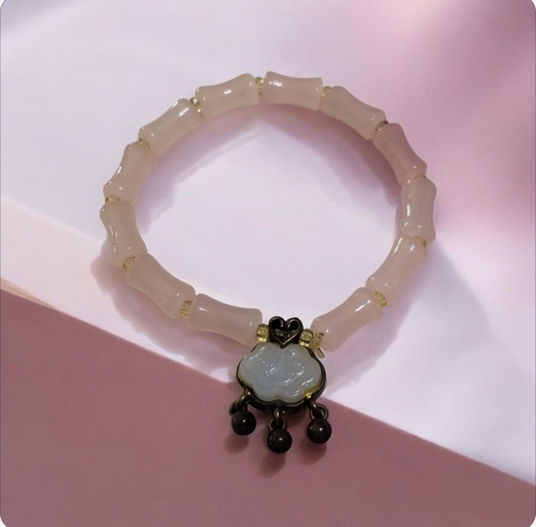 Harmonious Growth Bamboo & Protection Cloud Bracelet (Category: Bracelets) located in San Juan City. Submitted by exclusivelyours (Listing ID 1469791705, Image 1). Description: Crafted with smooth, blush-pink cylindrical bamboo-jointed beads, this piece symbolizes resilience, prosperity, and continuous growth. At its center hangs an antique-style accent adorned with a carved white jade-look Ruyi (Cloud Lock) charm and delicate dangling beads—a tr