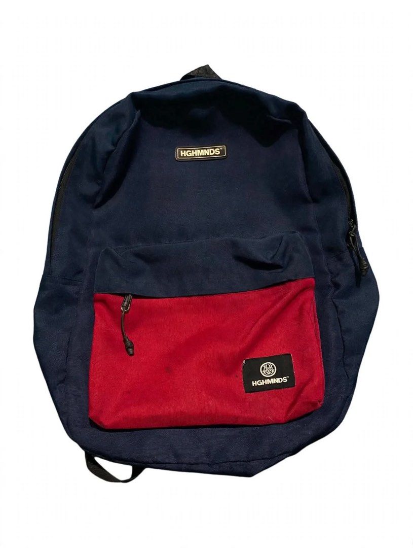 HGHMNDS Navy Blue Red Backpack (Category: Backpacks) located in Quezon City. Submitted by un0oo (Listing ID 1469923795, Image 1). Description: Navy blue backpack with a contrasting red front pocket. Two black woven labels featuring the HGHMNDS logo on the front. Adjustable black shoulder straps. Main compartment zips closed. Front zipped pocket keeps smaller items organized. Sturdy canvas material throughout..