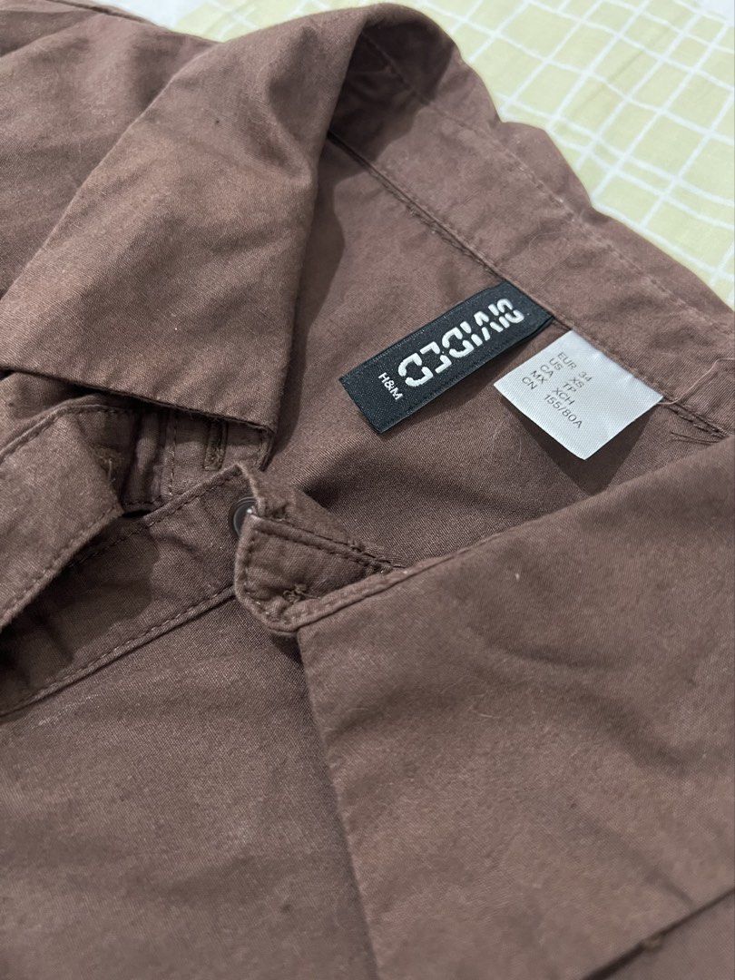 H&M Divided Brown Cropped Button-Up Shirt (Category: Shirts) located in Manila. Submitted by kirrsy (Listing ID 1469829487, Image 3). Description: - Brand/Model: H&M Divided - Size: EUR 34 / US XS - Color: Brown - Design: Collared neck, short sleeves, front button closure - Fit: Fitted bodice with curved hemline and smocked elastic back panel - Runs in XS Size: Bust: 74cm Waist: 64cm Length: 42cm I only do meet-ups or Lalamove deliveries within t