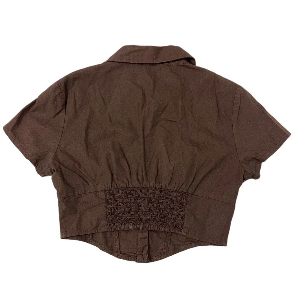 H&M Divided Brown Cropped Button-Up Shirt (Category: Shirts) located in Manila. Submitted by kirrsy (Listing ID 1469829487, Image 2). Description: - Brand/Model: H&M Divided - Size: EUR 34 / US XS - Color: Brown - Design: Collared neck, short sleeves, front button closure - Fit: Fitted bodice with curved hemline and smocked elastic back panel - Runs in XS Size: Bust: 74cm Waist: 64cm Length: 42cm I only do meet-ups or Lalamove deliveries within t