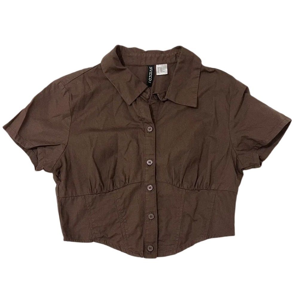 H&M Divided Brown Cropped Button-Up Shirt (Category: Shirts) located in Manila. Submitted by kirrsy (Listing ID 1469829487, Image 1). Description: - Brand/Model: H&M Divided - Size: EUR 34 / US XS - Color: Brown - Design: Collared neck, short sleeves, front button closure - Fit: Fitted bodice with curved hemline and smocked elastic back panel - Runs in XS Size: Bust: 74cm Waist: 64cm Length: 42cm I only do meet-ups or Lalamove deliveries within t