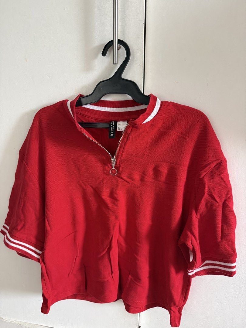 H&M Divided Red Half Zip Crop Top (Category: Shirts) located in San Mateo. Submitted by juliassss (Listing ID 1469806234, Image 1). Description: - Brand: H&M Divided - Size: S - Color/Pattern: Red crop top with white and red striped ribbed collar and cuffs - Design: Half zip neckline with round pull tab, boxy fit - Material: Cotton blend with textured weave - Condition: Good, minor storage wrinkles (easy to iron out).