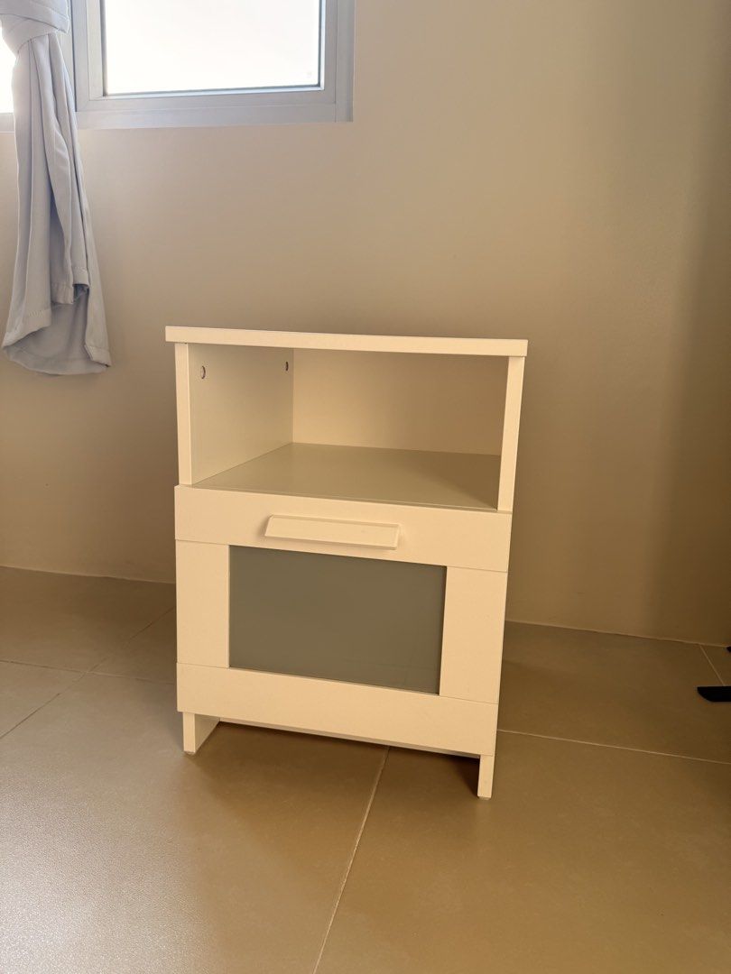 IKEA Nightstand White (Category: Shelves, Cabinets & Racks) located in Quezon City. Submitted by keenflower_35e25a (Listing ID 1469819880, Image 1). Description: - Authentic IKEA BRIMNES white nightstand - Dimensions: 39x41x53 cm - Features a convenient open top compartment and one lower drawer - Stylish frosted glass panel insert on the drawer - Clean, modern design that fits any bedroom setup.