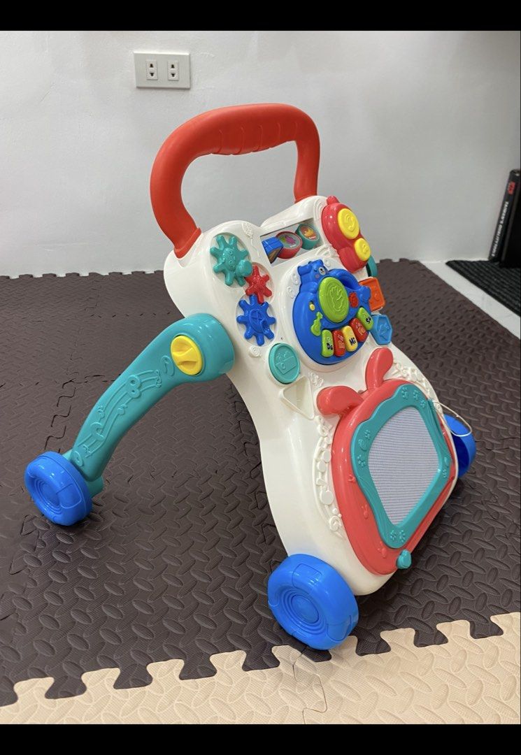 Interactive Multi-Activity Baby Walker with Drawing Board and Toys (Category: Infant Playtime) located in Manila. Submitted by almondchi05 (Listing ID 1469830054, Image 2). Description: All-in-one baby walker and interactive learning center featuring piano keys, gears, shapes, a phone toy, and a built-in erasable drawing board. Designed with a stable four-wheel base and sturdy handle to safely support your toddler's first steps..