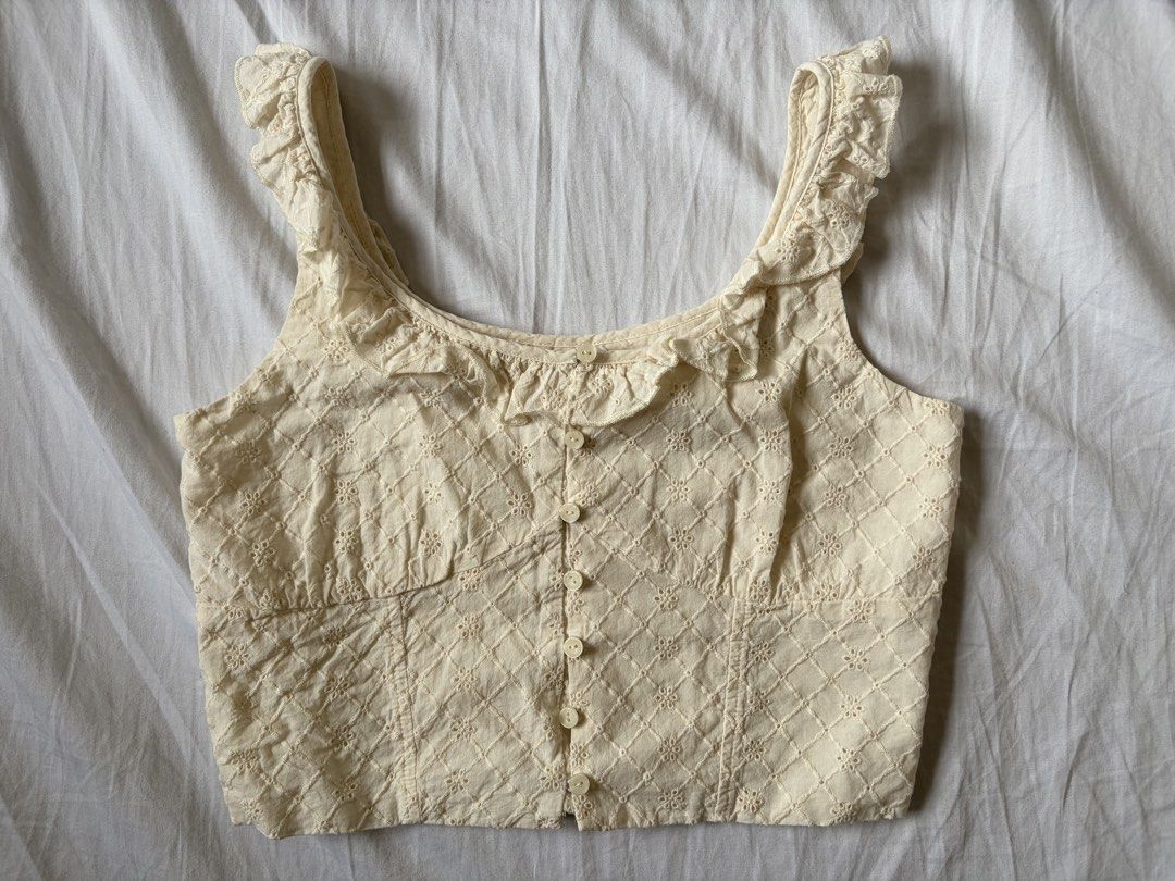 Just G Cream Eyelet Ruffle Crop Top (Category: Sleeveless) located in Quezon City. Submitted by vidadmarie (Listing ID 1469819026, Image 1). Description: - Brand/Model: Just G - Size: XXS - Color: Cream - Design: Eyelet pattern with diamond embroidery - Details: Ruffled scoop neckline and straps, front button-up closure with small white buttons - Fit: Cropped length, ideal for pairing with high-waisted denim or skirts.
