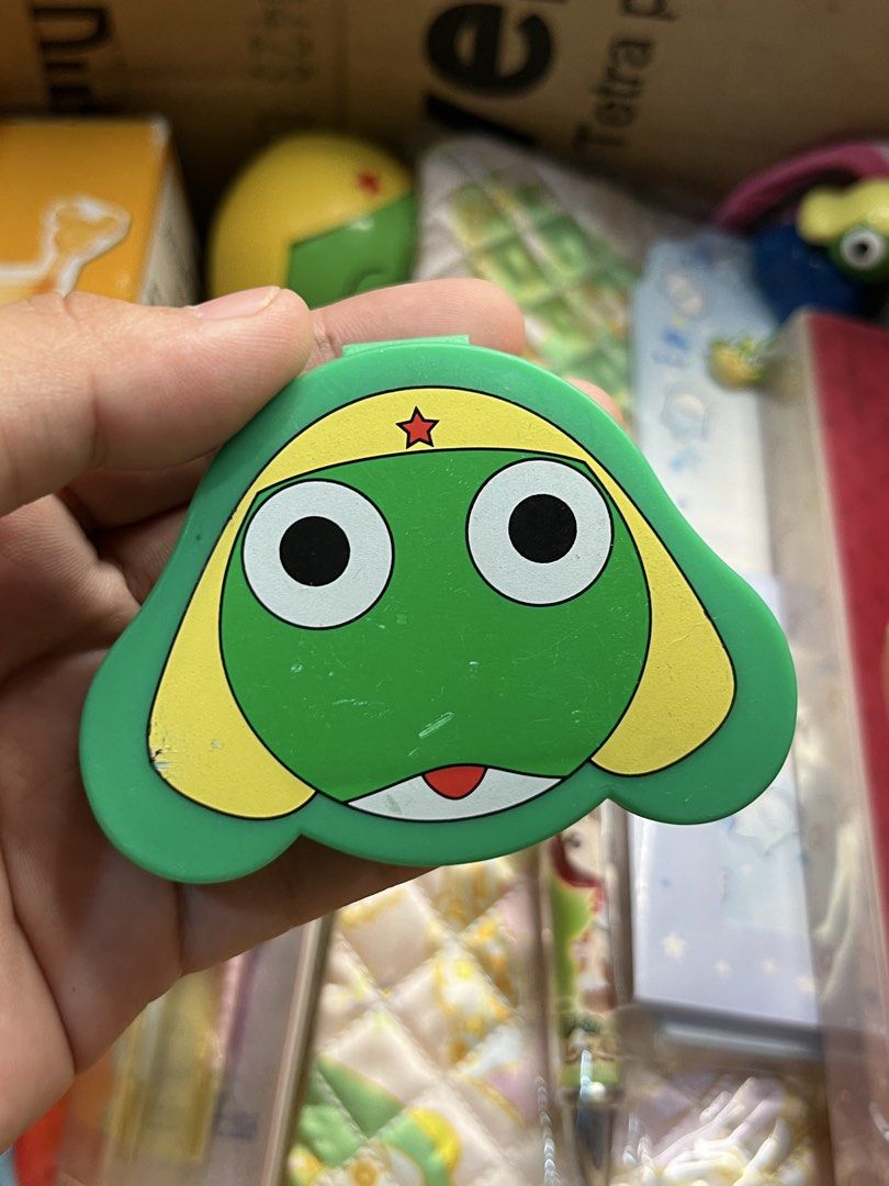 Keroro Gunso Green Plastic Character Case (Category: Designer & Blind Box Toys) located in Gapan. Submitted by lunashop14 (Listing ID 1469802029, Image 1). Description: - Official-style Keroro character head design in green plastic - Features iconic yellow markings and red star on the forehead - Interior features built-in square compartment walls - Compact size makes it easy to toss into your bag - Plastic hinge is fully functional - Condition: M