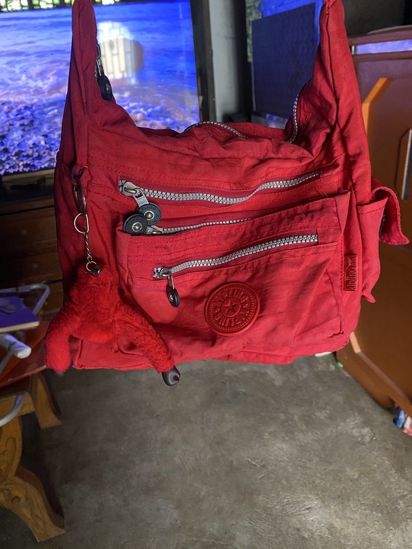 Kipling Red Nylon Crossbody Shoulder Bag with Monkey Keychain (Category: Cross-body Bags) located in San Miguel. Submitted by lirika01 (Listing ID 1469806252, Image 1). Description: Bright red Kipling shoulder bag made of durable crinkled nylon. Multiple exterior zip pockets for easy organization. Includes the signature fuzzy red monkey keychain dangling from the side ring. Adjustable strap for crossbody or shoulder wear. Main compartment lined i