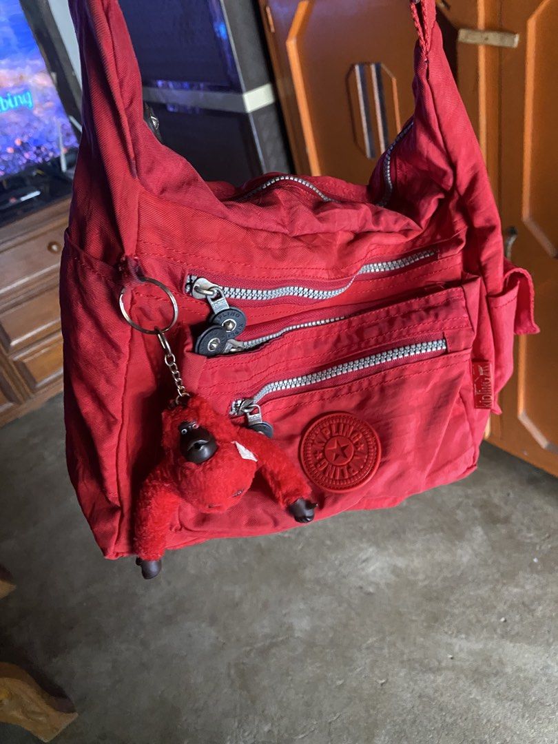 Kipling Red Nylon Crossbody Shoulder Bag with Monkey Keychain (Category: Cross-body Bags) located in San Miguel. Submitted by lirika01 (Listing ID 1469806252, Image 3). Description: Bright red Kipling shoulder bag made of durable crinkled nylon. Multiple exterior zip pockets for easy organization. Includes the signature fuzzy red monkey keychain dangling from the side ring. Adjustable strap for crossbody or shoulder wear. Main compartment lined i