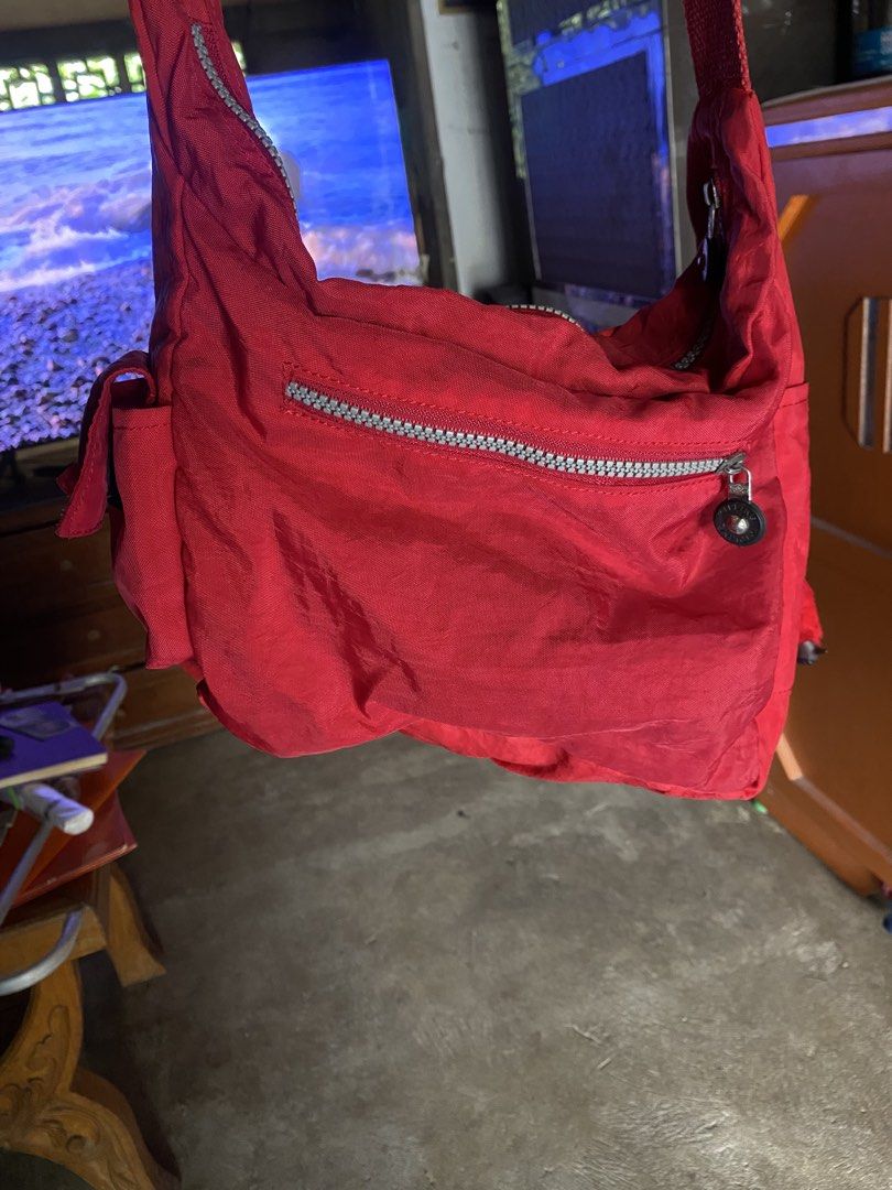 Kipling Red Nylon Crossbody Shoulder Bag with Monkey Keychain (Category: Cross-body Bags) located in San Miguel. Submitted by lirika01 (Listing ID 1469806252, Image 2). Description: Bright red Kipling shoulder bag made of durable crinkled nylon. Multiple exterior zip pockets for easy organization. Includes the signature fuzzy red monkey keychain dangling from the side ring. Adjustable strap for crossbody or shoulder wear. Main compartment lined i