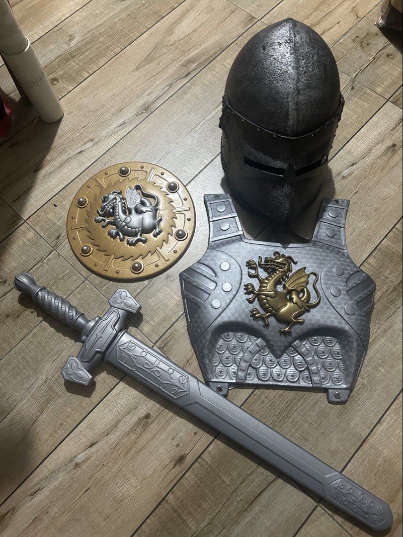 Knight Armor Costume Set Helmet Shield Sword Scabbard (Category: Combat Sports) located in Paranaque City. Submitted by zac.sei (Listing ID 1469804968, Image 1). Description: - Complete medieval knight dress-up set - Includes textured dark grey helmet with visor slits - Silver chest armor featuring a gold dragon emblem - Round gold and silver shield with dragon motif - Long silver sword with matching scabbard - Durable plastic construction - Idea