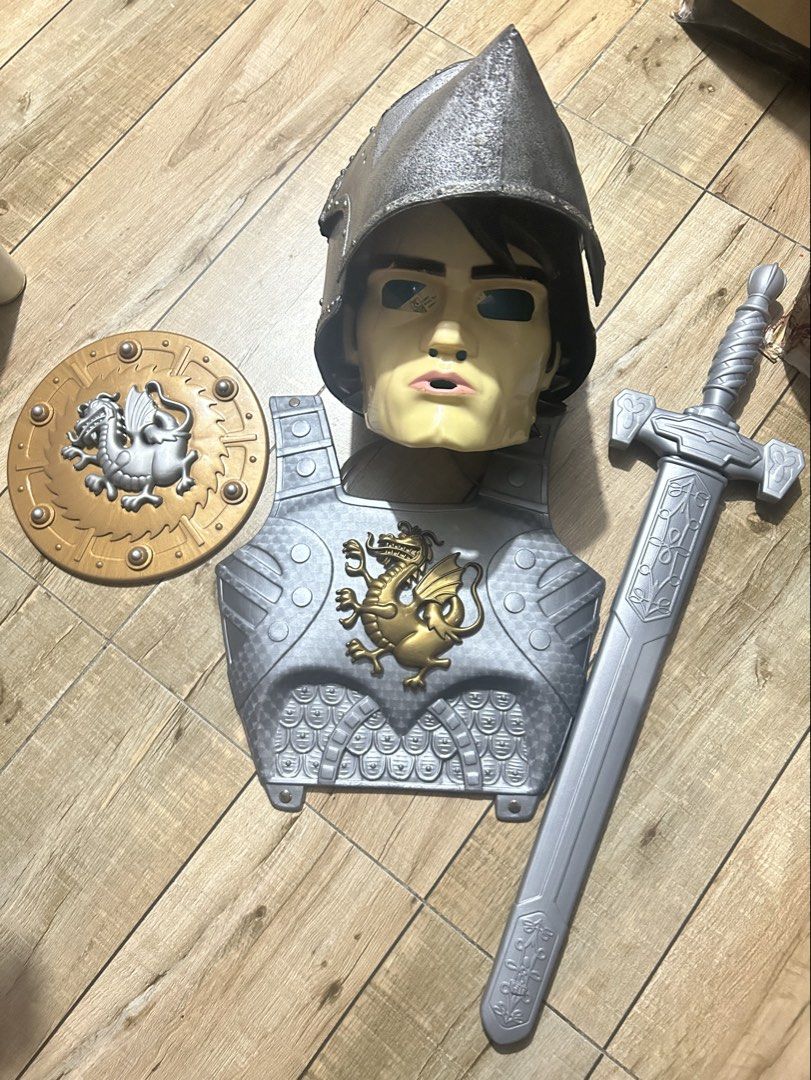 Knight Armor Costume Set Helmet Shield Sword Scabbard (Category: Combat Sports) located in Paranaque City. Submitted by zac.sei (Listing ID 1469804968, Image 2). Description: - Complete medieval knight dress-up set - Includes textured dark grey helmet with visor slits - Silver chest armor featuring a gold dragon emblem - Round gold and silver shield with dragon motif - Long silver sword with matching scabbard - Durable plastic construction - Idea