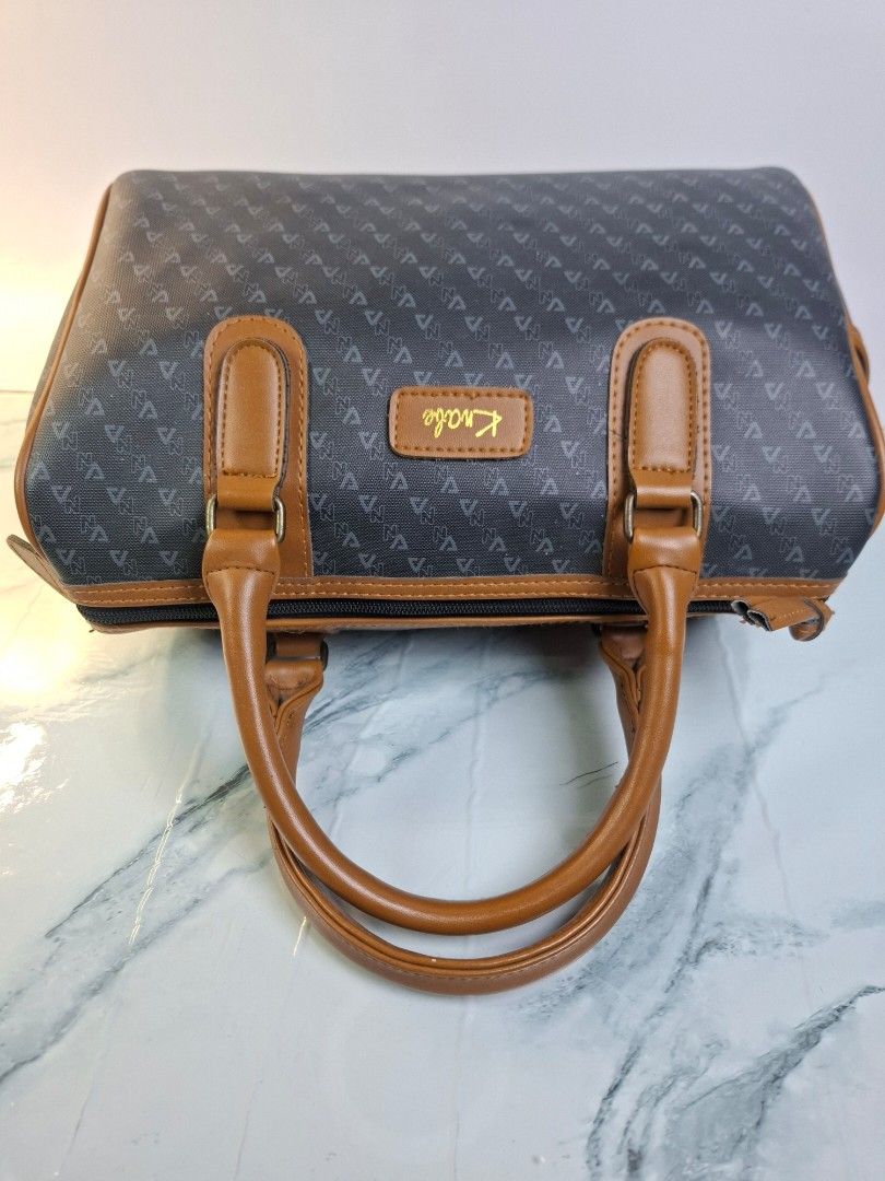 Kriabe Monogram Handbag Brown Grey (Category: Purses & Pouches) located in Pasay City. Submitted by onick_79 (Listing ID 1469931092, Image 3). Description: -Dimensions: L 29 x H 19 x W 14 cm - Brand: Kriabe - Color/Pattern: Dark grey with all-over monogram - Material/Trim: Brown faux leather trim - Handles: Dual top handles - Details: Gold lettering logo patch on the front - Closure: Zip top closure - Condition: Clean inside and out, sturdy struc